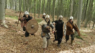 Warriors of Vikings are running in the forest on the battle.