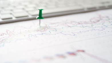 Businessman sets multicolored pins on the financial report graph