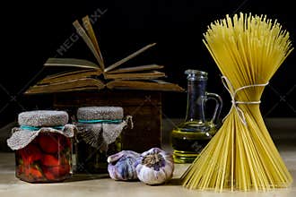 Pasta and olive oil on an old kitchen table. Recipes in old books in the kitchen on a wooden table.