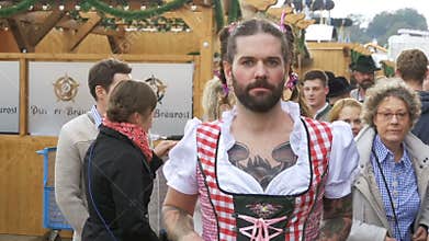 Drunken man in a street dressed in a female dirndl is having fun at the Oktoberfest. Bavaria. Slow Motion