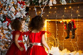 Two curly little girls looking at the christmas fireplace near b
