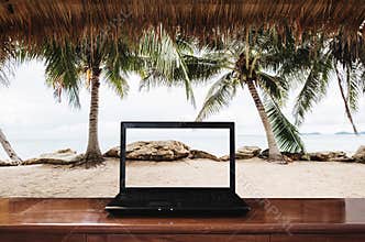 Laptop computer on wooden table with at the beach