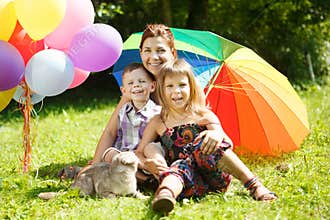 Happy family in the park. Mother, daughter and son are sitting o