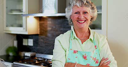 Senior woman standing with arms crossed in kitchen 4k