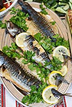 Fish cooked on fire on a plate with leaves parsley and lemon.