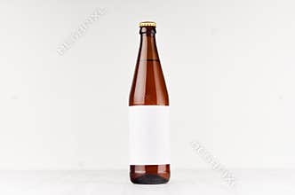 Brown NRW beer bottle 500ml with blank white label on white wooden board, mock up.