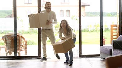 Happy couple carrying boxes entering new house, home owners moving