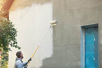 House painter painting building exterior with roller