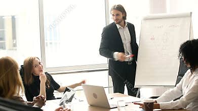 Confident businessman giving presentation on flipchart to colleagues in boardroom