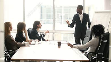 Dark-skinned businessman giving presentation to partners at meeting in boardroom