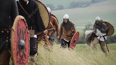 Group of Medieval Viking with shields walking forward on the meadow