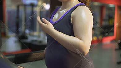 Strong overweight woman working hard to lose weight, sweating on treadmill