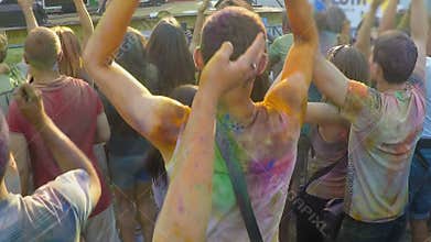 Happy audience covered in colorful paint enjoying concert at outdoor festival