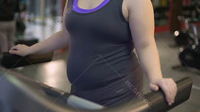 Woman fighting obesity in gym, exercising on treadmill, workout for healthy body