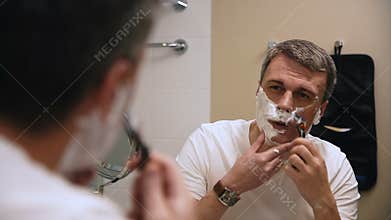 Adult man shaving in bathroom
