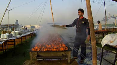 Young man prepares BBQ in large quantity