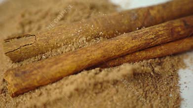 Cinnamon sticks falling into cinnamon powder in slow motion