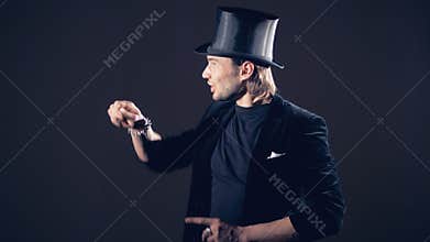 Magician is making a sparkling crystal disappear from his right fist and taking from the air.