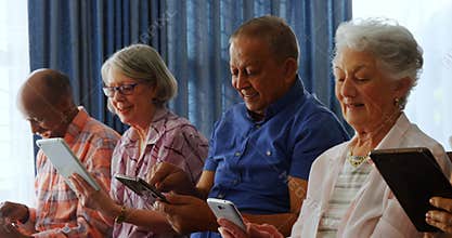Happy senior friends using digital tablet in living room 4k