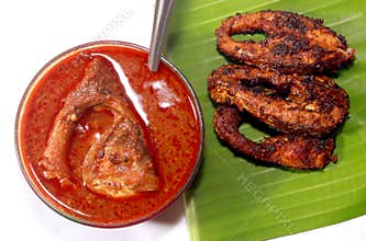 Meen kulambu with fish fry on a leaf.
