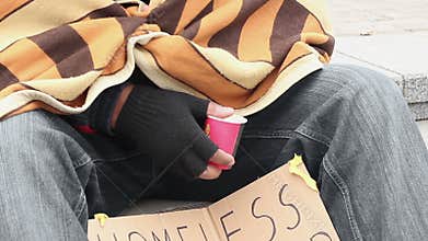 Frozen homeless man covered with blanket, begging money, holding paper cup