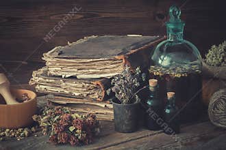 Tincture bottles, assortment of dried healthy herbs, old books, wooden mortar, sack of medicinal herbs. Herbal medicine.