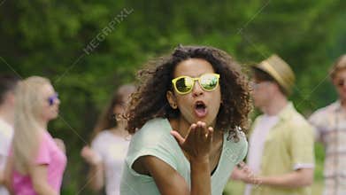 Young biracial actress sending air kiss at camera and dancing at outdoor party