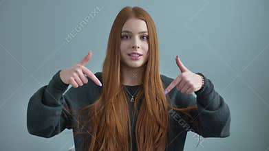 Young beautiful red-haired girl blogger, waving her hand at the camera, asks to subscribe to the channel, write a