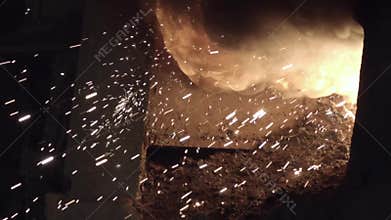 Metal sparks fly from the furnace