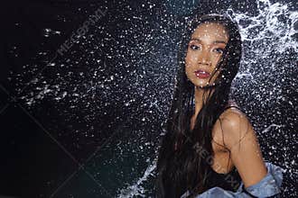 Active Woman rain coat with Water Splash over studio lighting bl