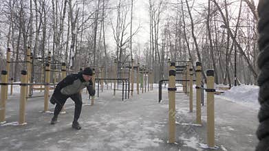 Athlete man doing crossfit exercise with expander on outdoor winter training