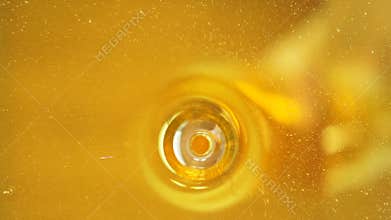 A stream of honey flows into a glass jar, close-up