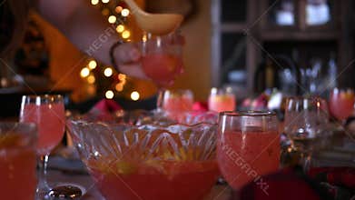 Woman scoops up lemonade from punch bowl to fill glasses at Christmas table