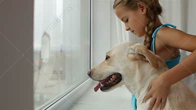 Girl with dog looking out the window