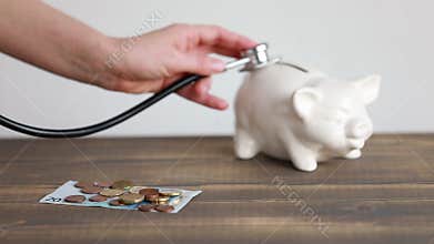 Health expenses concept, money on the desk and piggy bank with stetoscope