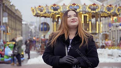 Beautiful fat woman stands against carousel background