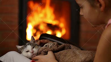 Young girl with rescue kitten at the fireplace
