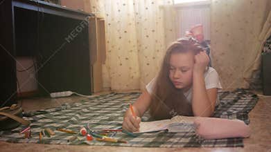 Girl teen who spend time at home drawing while lying on the floor
