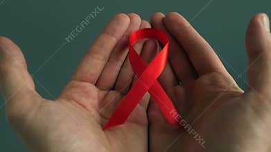 HIV/AIDS red awareness ribbon in the hands.