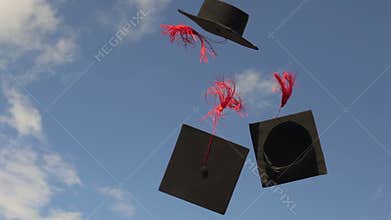 Mortarboards flying in blue sky, university tradition to throw academic caps up