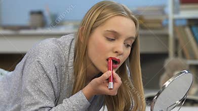 Insecure teenage girl applying red lipstick, trying to improve self-esteem