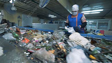 Female factory employee is sorting waste for further recycling. Waste recycling plant.