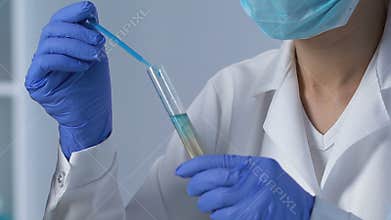 Lab assistant adding reactant to drinking water sample to determine sediments