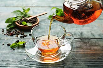 Pouring black tea into glass cup