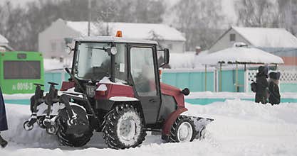 Tractor Cleaning Snow In Winter Snowy Day In City. Winter Service Vehicle In Work. Snow Removal Vehicle