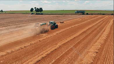 Aerial view of tractor with combine harvester that makes stakes of hay. Harvest of wheat field Agriculture and