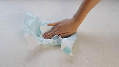 Girl napkin touches baby diaper, soaking, close-up
