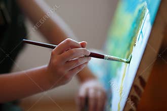 Preschool girl painting in art class. Close up photo brush in hand
