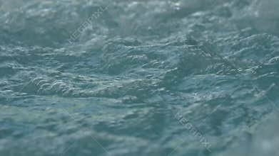 Blue clear rippled water with bubbles in jacuzzi. slow motion