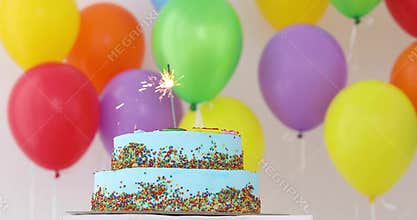 Blue Birthday cake with sparkler and colorful balloons